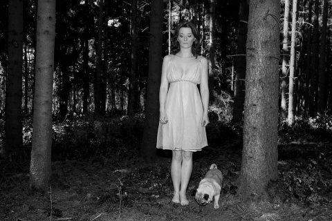 eine frau mit einem mops im wald